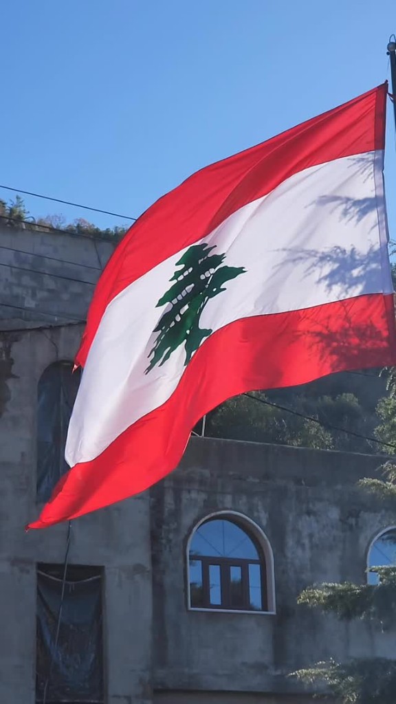 Lebanese flag waving in front of a stone building